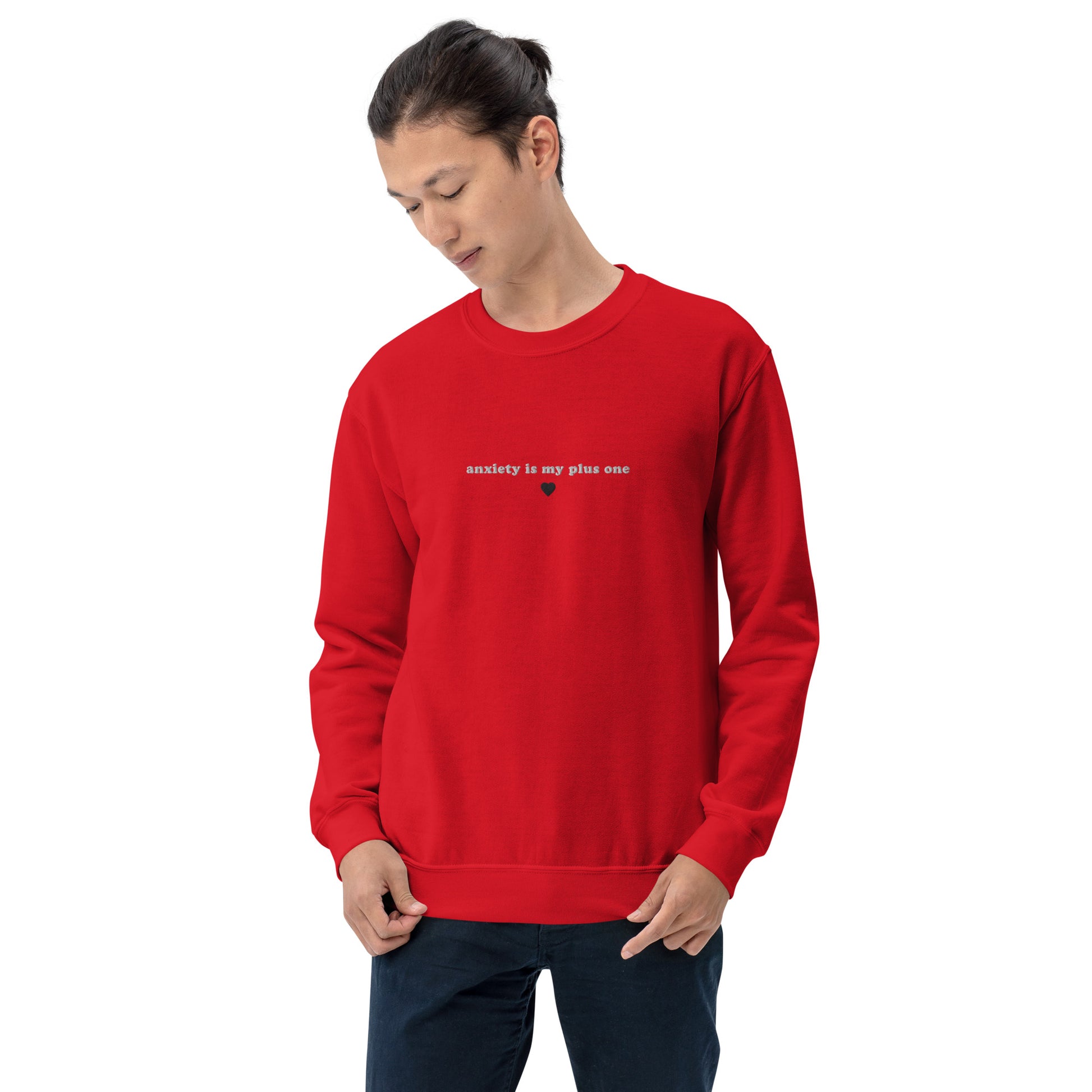 Man model wearing a red embroidered unisex crewneck sweatshirt with 'anxiety is my plus one' text, perfect for mental health awareness and self-expression.